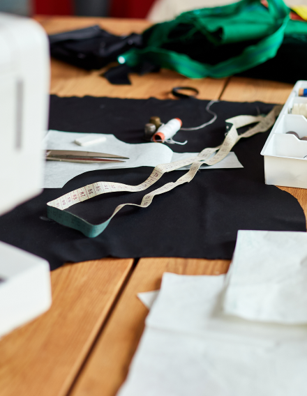 Sewing materials on a wooden table, including fabric, measuring tape, and scissors.