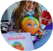 A child holding a colorful doll and book with a vibrant hijab design.