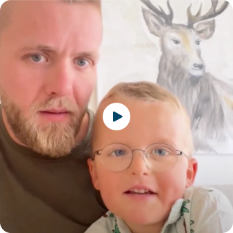 Man and child smiling with a deer painting in the background.