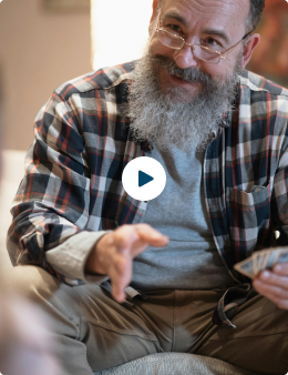 A bearded man in a plaid shirt playing cards.