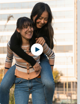 Two people happily giving and receiving a piggyback ride outdoors.