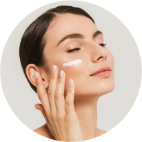 Woman applying skincare cream to her cheek.