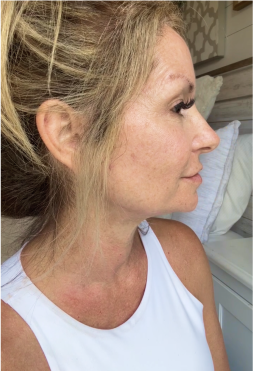 A woman in profile view wearing a white top indoors.
