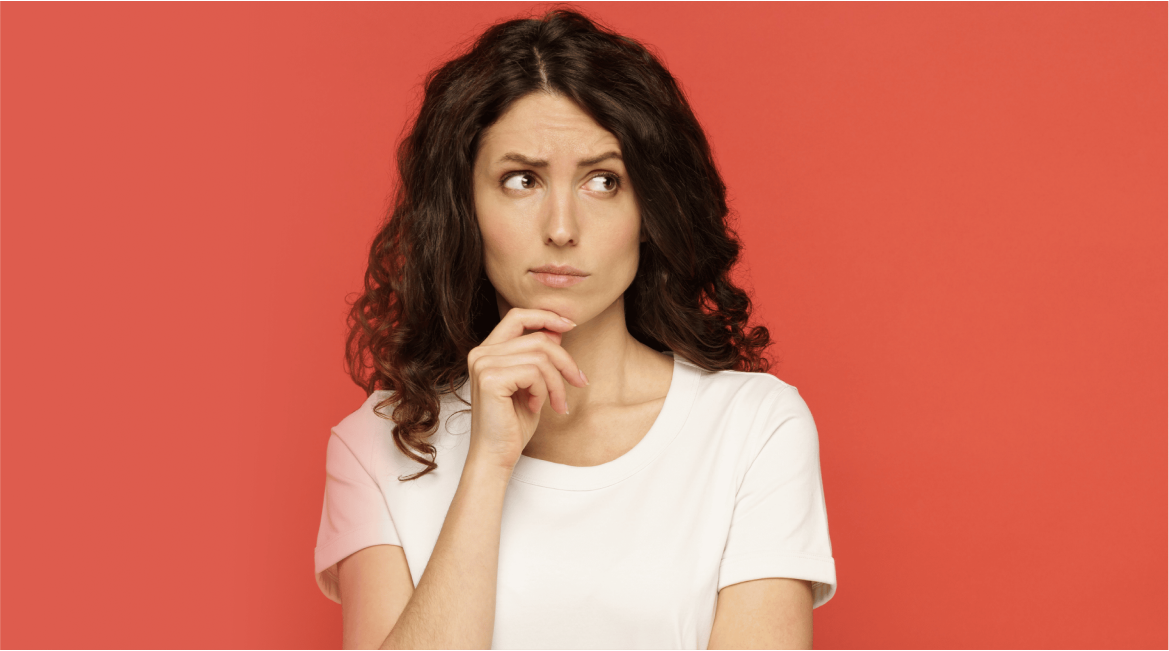 Woman in a white shirt looking thoughtful against a red background.