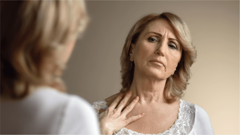 A thoughtful woman looks at herself in the mirror.