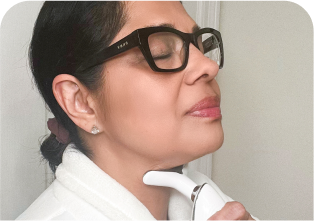 Woman using a skincare device on her neck.
