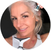 Woman using a skincare device, smiling at the camera.