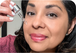 Woman applying skincare serum to her face with a dropper.