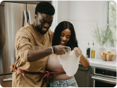 Couple happily making dough together in a modern kitchen.