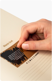 A hand scratching off a black layer over text on a card.