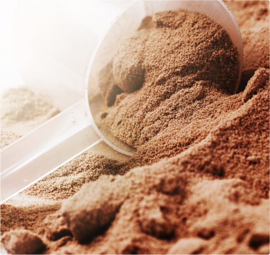 A scoop of brown protein powder spilling on a surface.