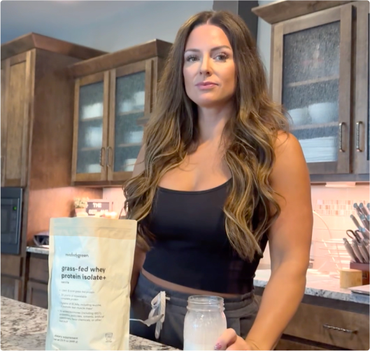 Woman in a kitchen with grass-fed whey protein.