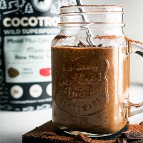 Mason jar filled with a chocolate smoothie, with product packaging in the background.