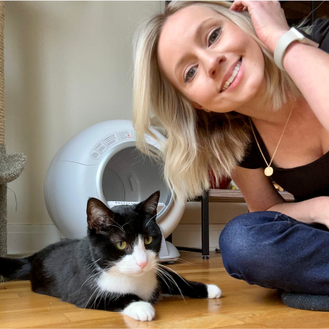 Woman smiling with a black and white cat indoors.