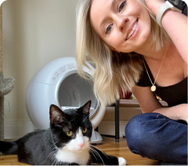Woman smiling with a black and white cat indoors.