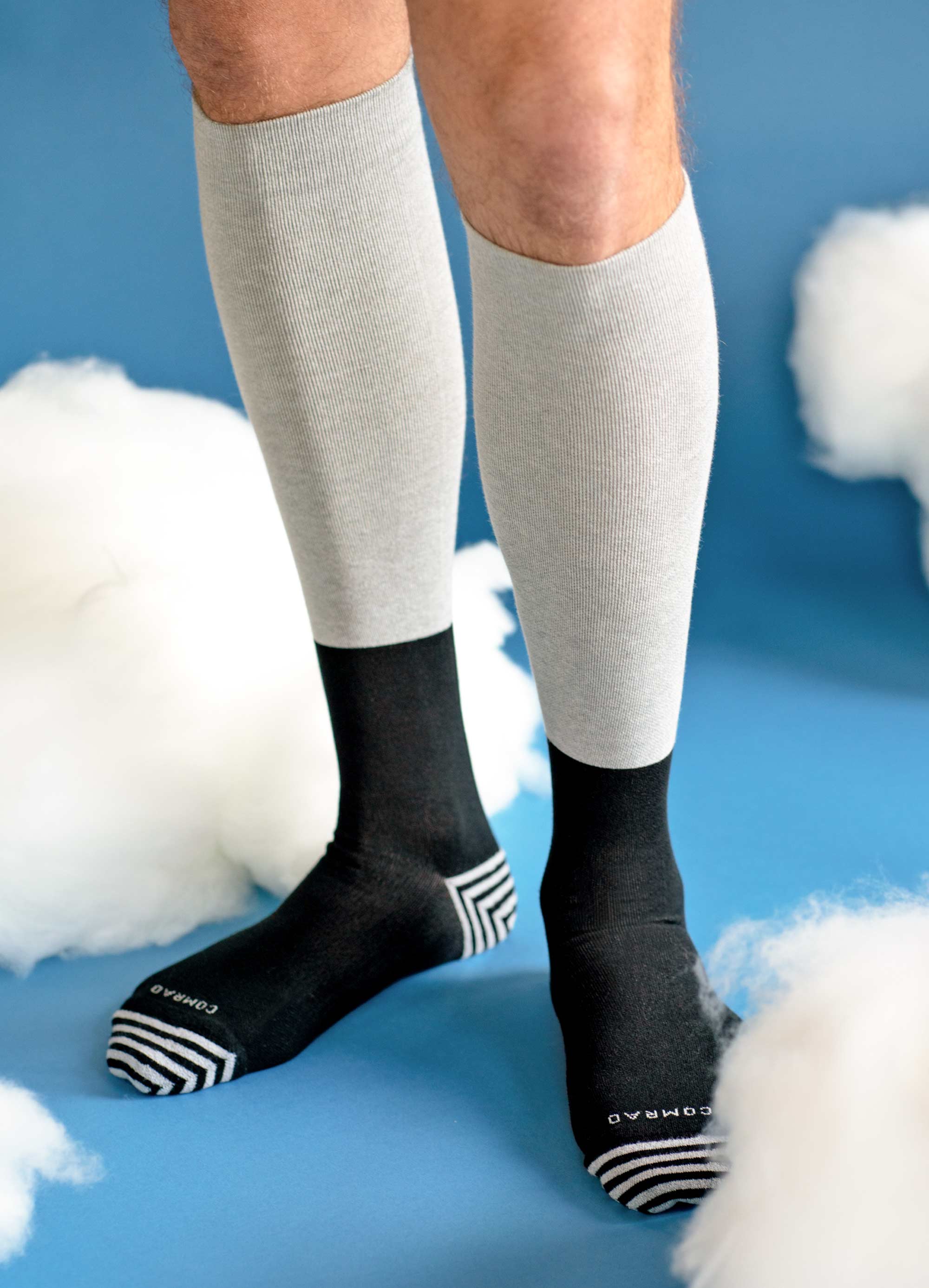 Person wearing gray and black knee-high socks on a blue background with clouds.