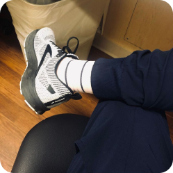 Customer wearing white striped compression socks with sneakers and navy scrubs