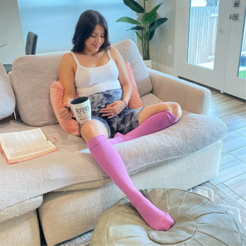 Pregnant woman drinking coffee with Comrad compression socks on