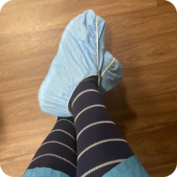 Customer wearing navy striped compression socks with blue disposable shoe covers