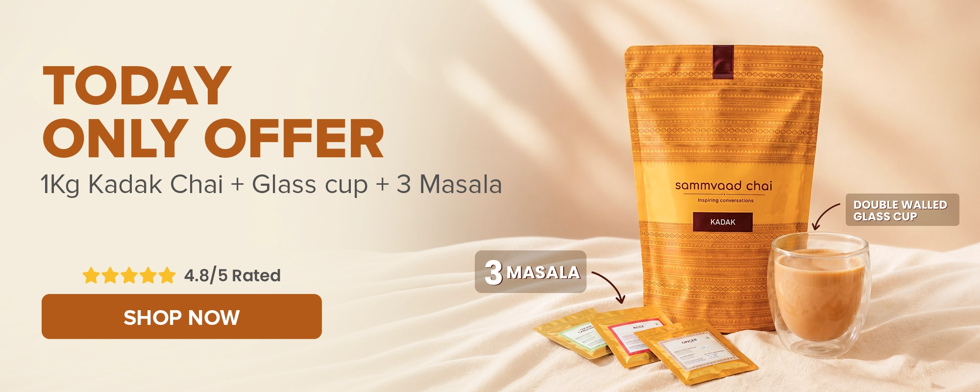 A pouch of sammvaad chai, a double-walled glass cup with tea, and three masala packets.