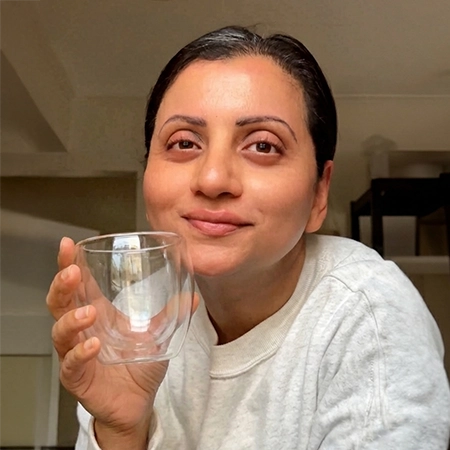 Double-walled glass cup containing a beverage; highlights include heat resistance, microwave safety, and borosilicate material.