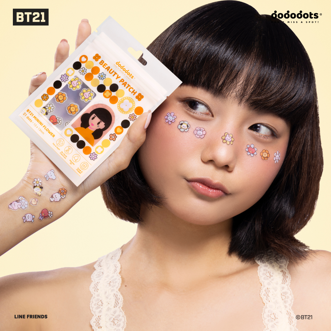 A woman with flower-shaped beauty patches on her face holds up the packaging for the product.
