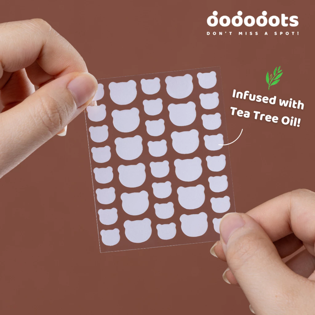 Hands holding a sheet of bear-shaped stickers infused with tea tree oil.