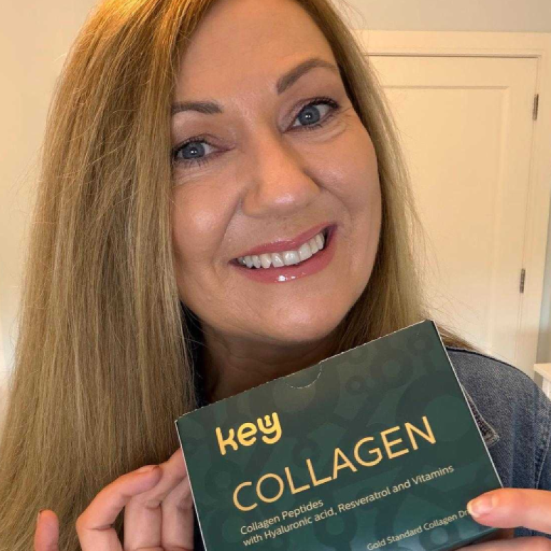 A smiling woman with long, light brown hair holds a green box of Key Collagen.