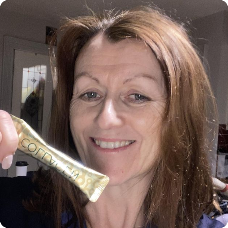 A smiling woman with reddish-brown hair holds up a gold sachet of collagen.