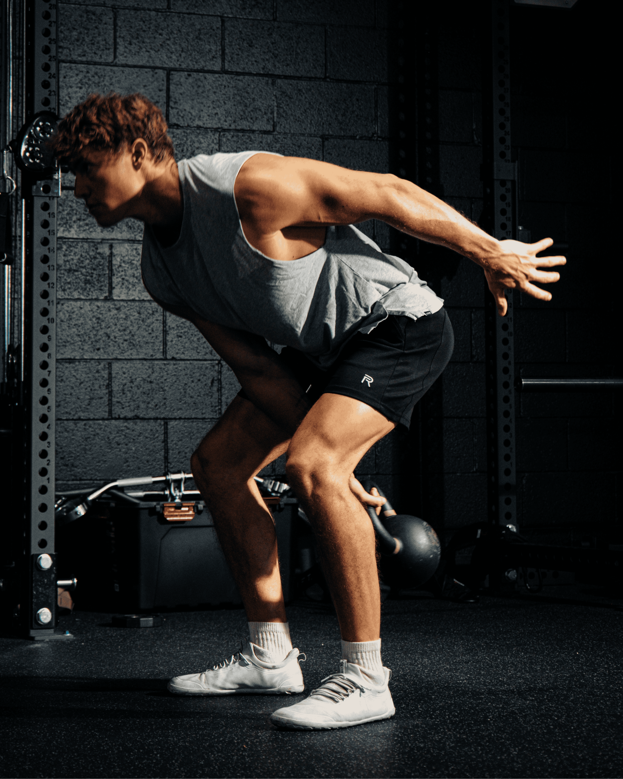 A man in a gym is in the middle of performing a kettlebell swing exercise.