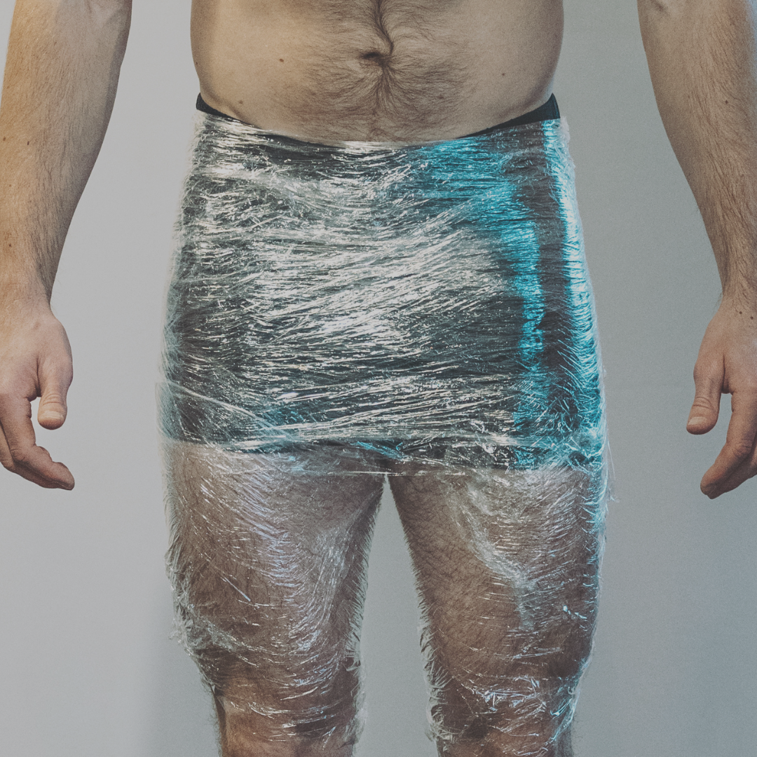 Person wrapped in clear plastic wrap from waist to thighs.