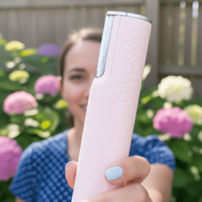 Person holding a pink device in front of hydrangea flowers.