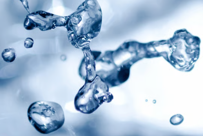 Close-up of water droplets in mid-air against a light background.