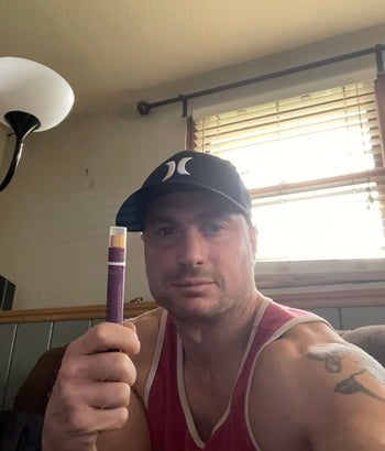 Man holding a purple object in a home with a lamp in the background.