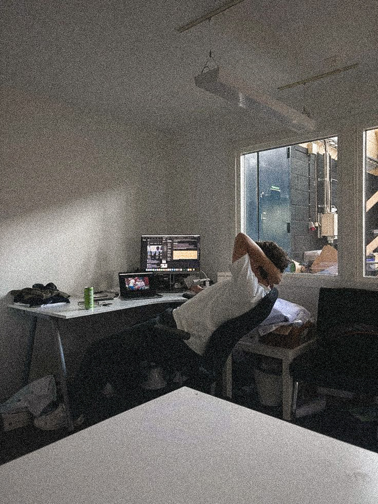 Person sitting at a desk with computer monitors displaying editing software.