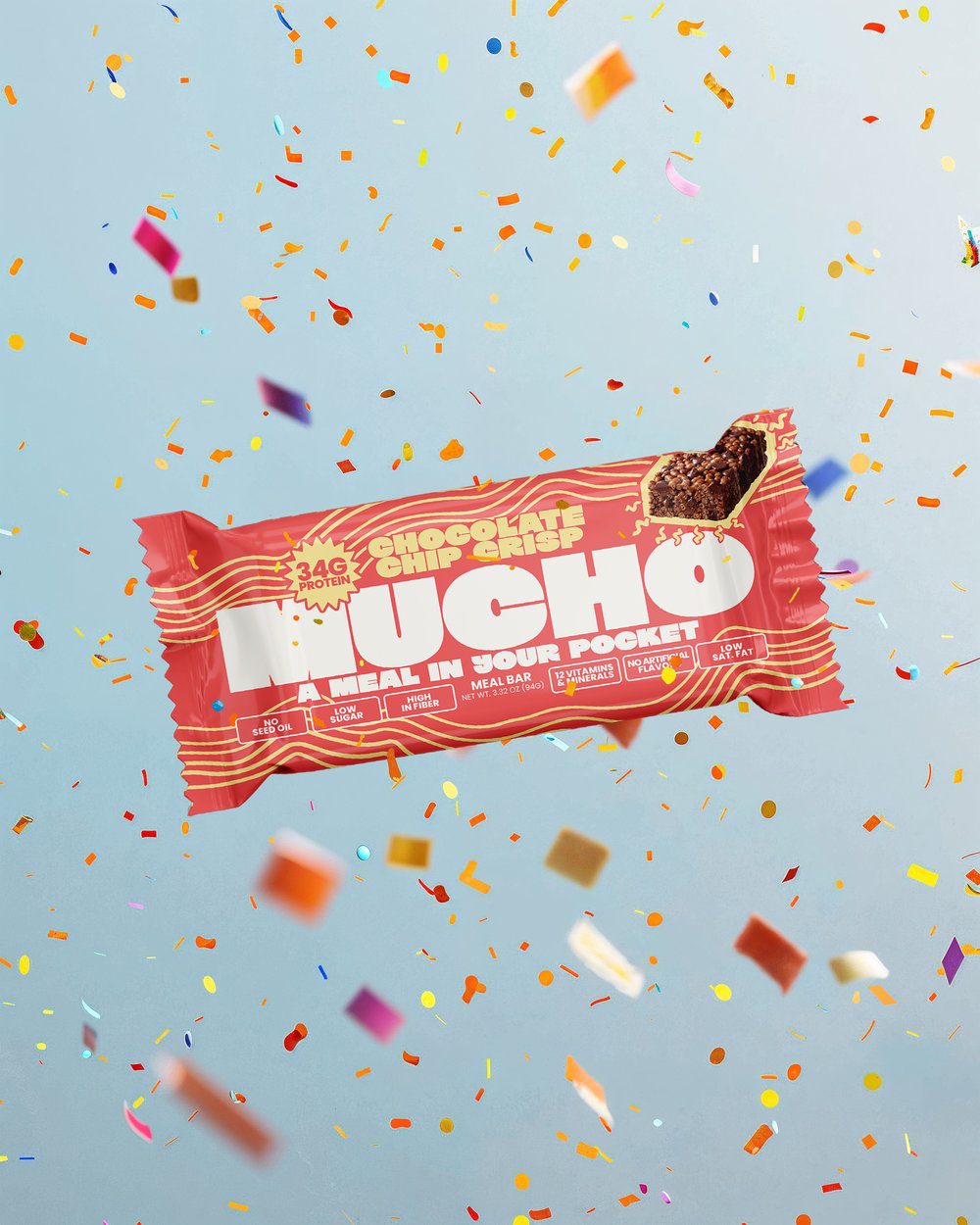 A Mucho Chocolate Chip Crisp protein bar with a bite taken out, floating amidst falling confetti.