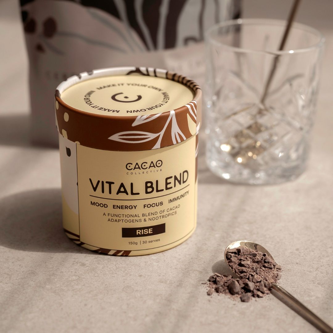 Container of cacao blend with a spoon and glass nearby.