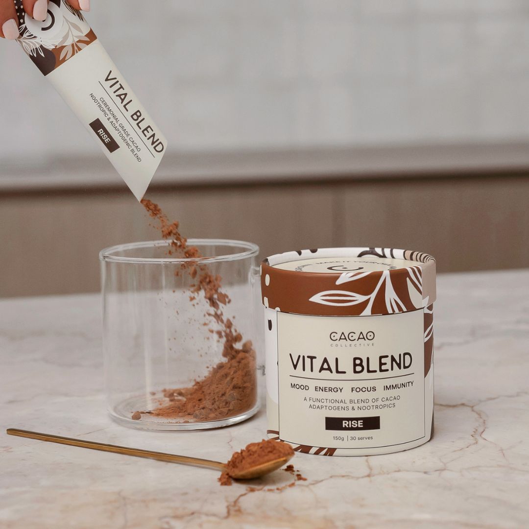 Pouring Vital Blend cacao powder into a glass on a marble countertop.