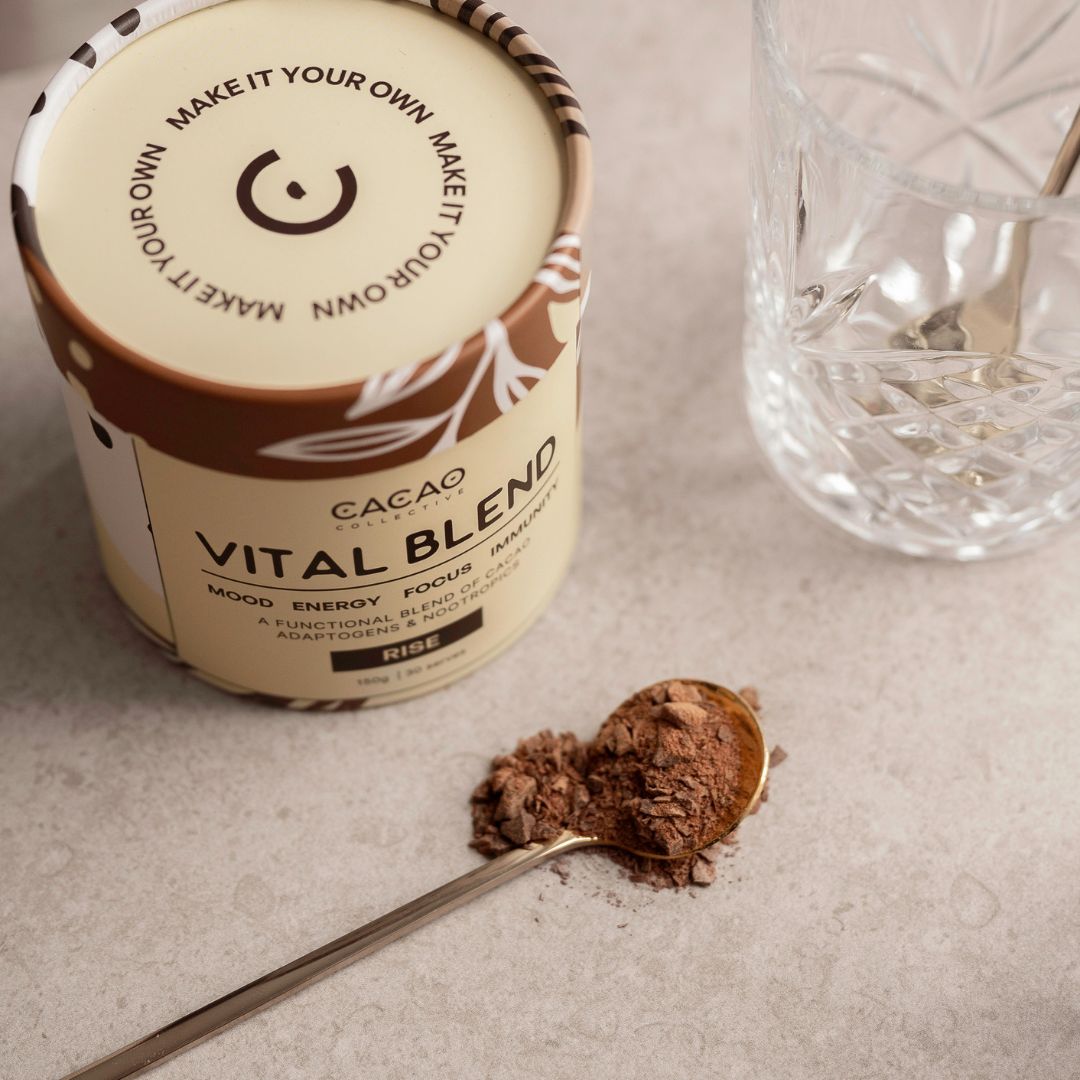 A Vital Blend container, spoon with powder, and a glass on a table.