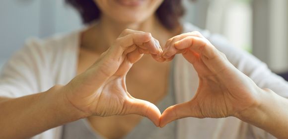 Person forming a heart shape with hands.