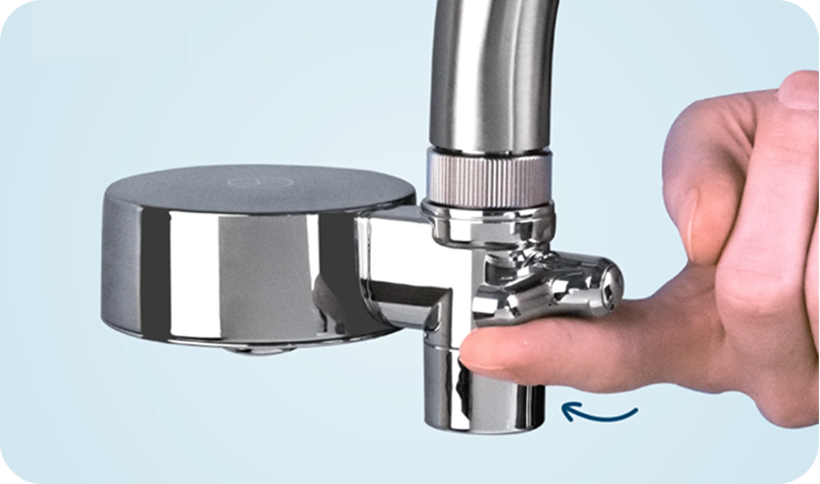 A close-up of a hand turning a lever on a chrome, faucet-mounted water filtration system.