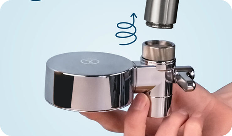 A hand holds a chrome faucet attachment, showing how it screws onto the faucet above.