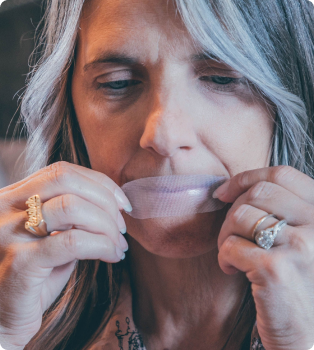 Person placing tape over their mouth.