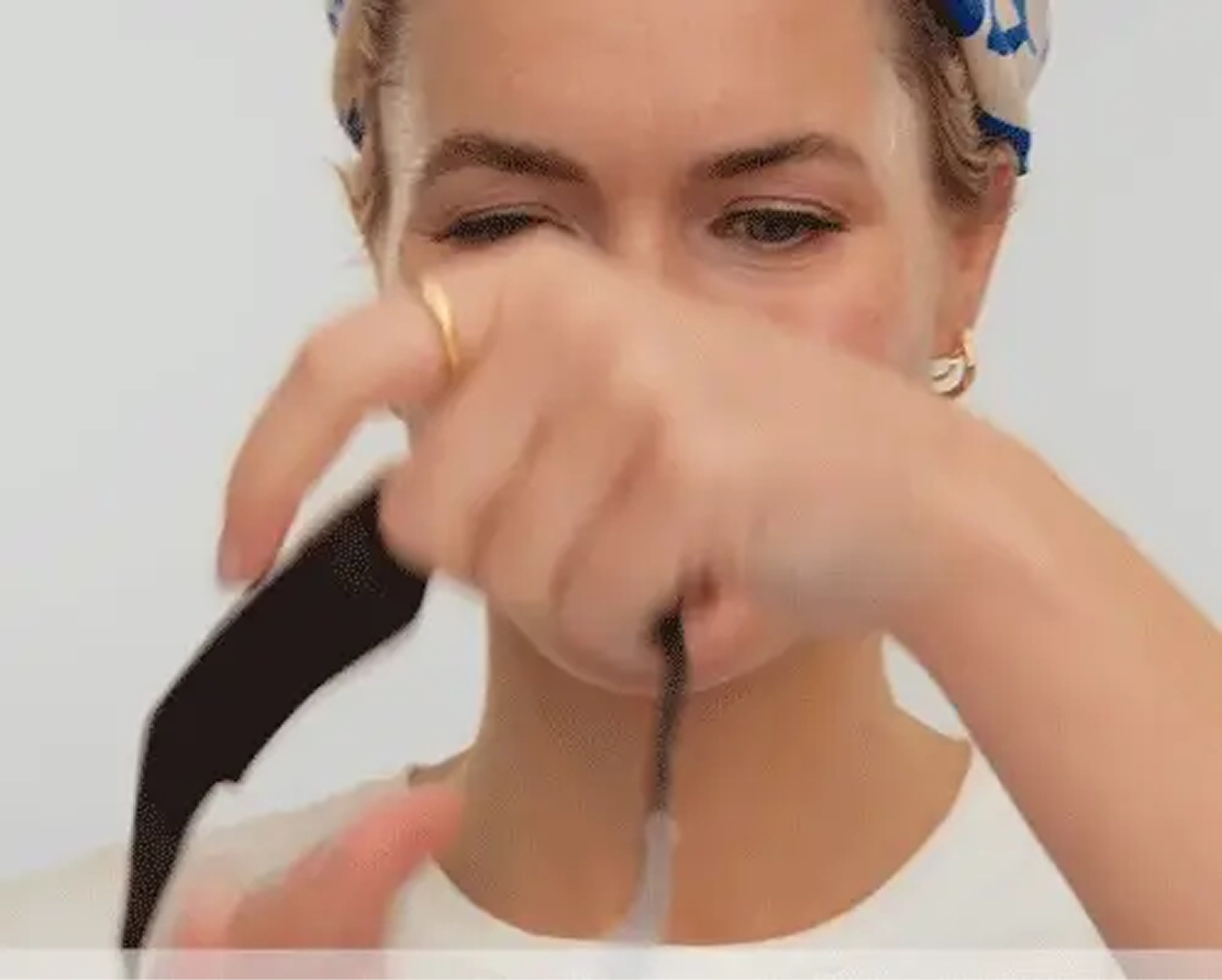 Person with headscarf holding a black object.