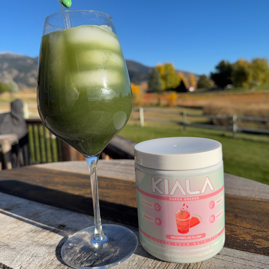 A green drink in a wine glass next to a supplement container outdoors.