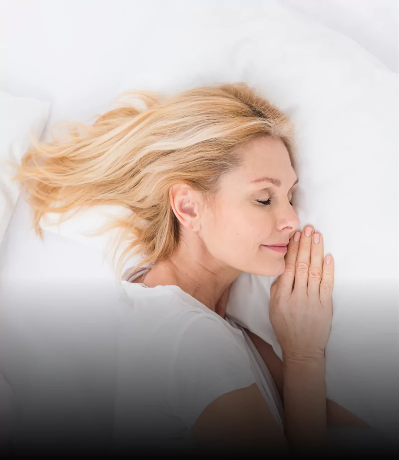 Woman with blonde hair sleeping peacefully on a white pillow.