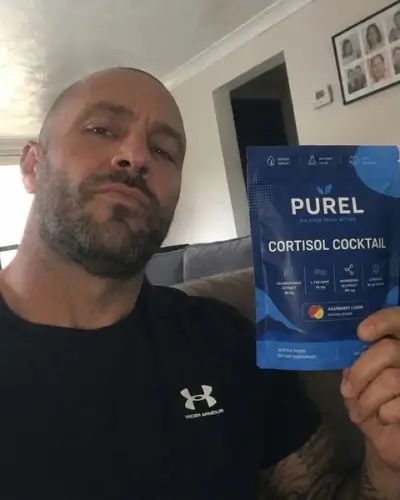 A bald man with a beard holds up a blue pouch of Purel Cortisol Cocktail.
