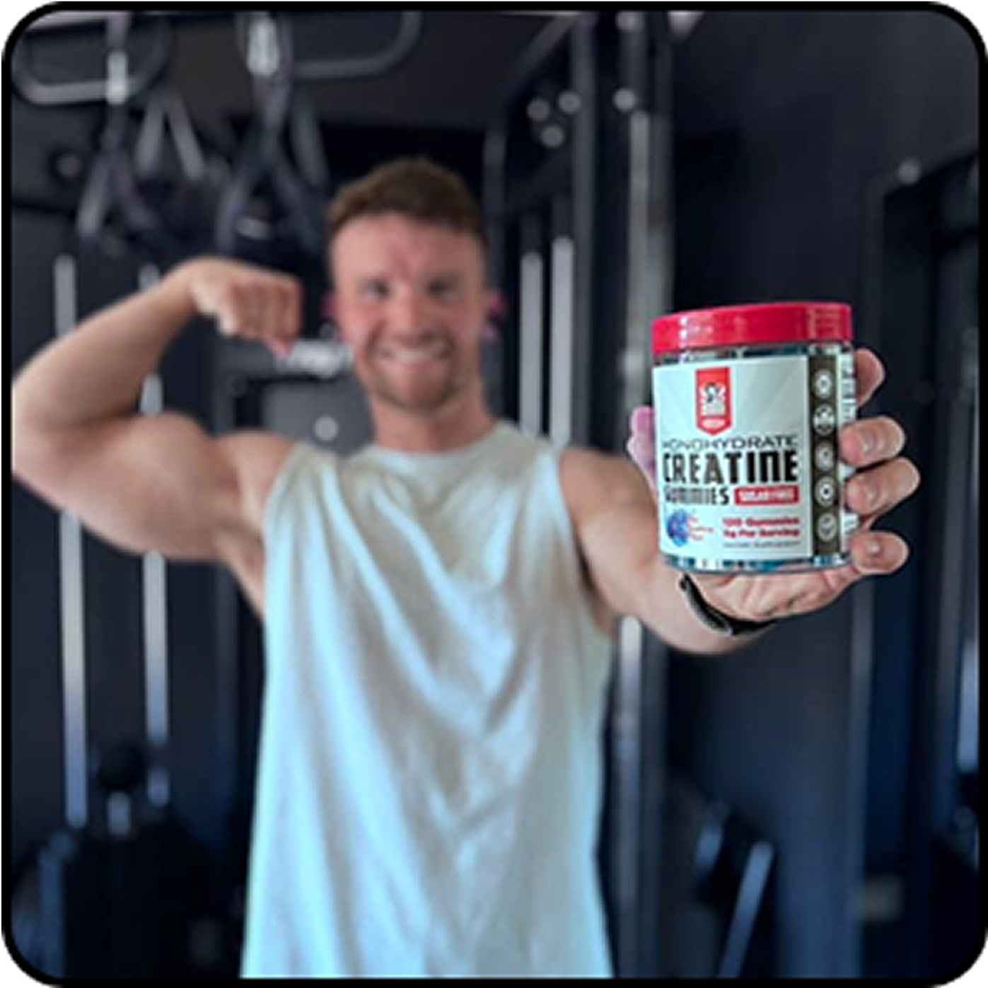 Person flexing arm and holding a creatine supplement container in a gym.