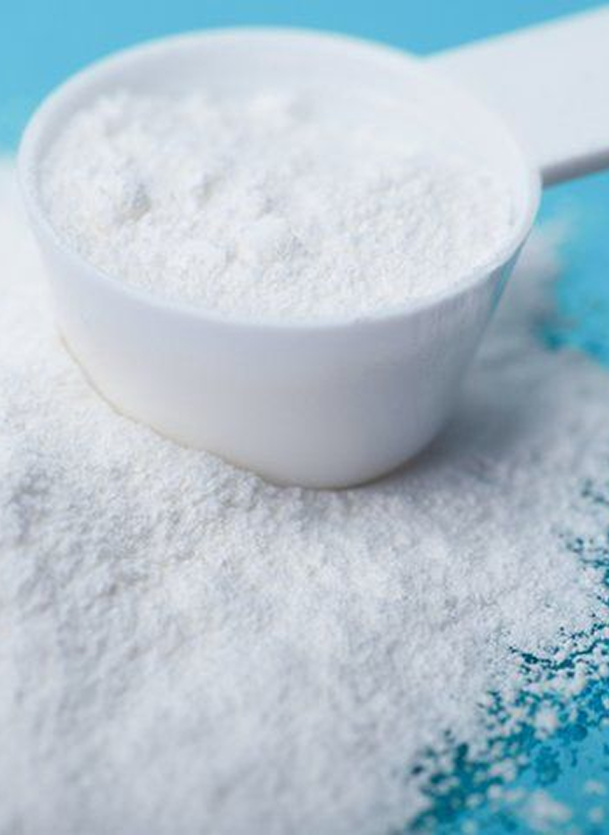 White powder in a measuring scoop on a blue surface.
