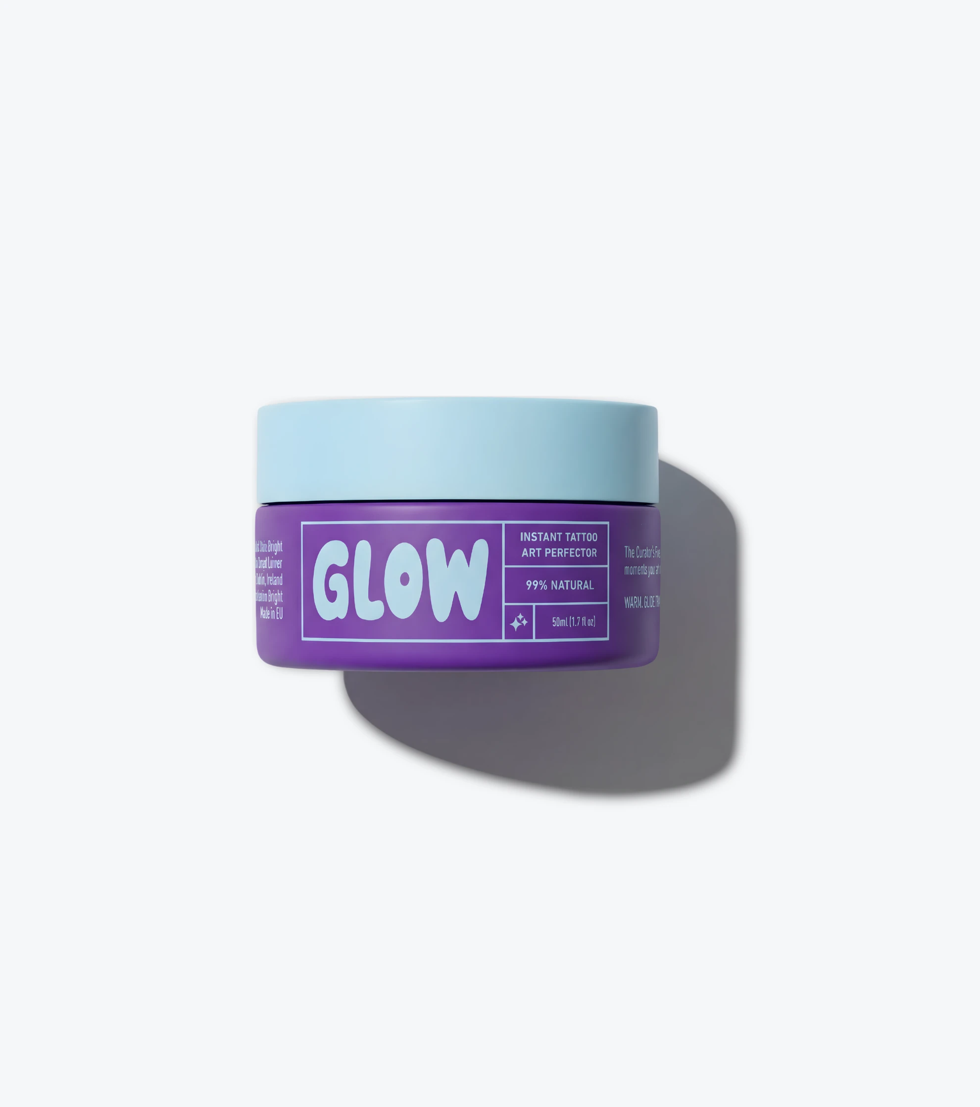 A purple jar of GLOW tattoo perfector cream with a light blue lid, on a plain background.